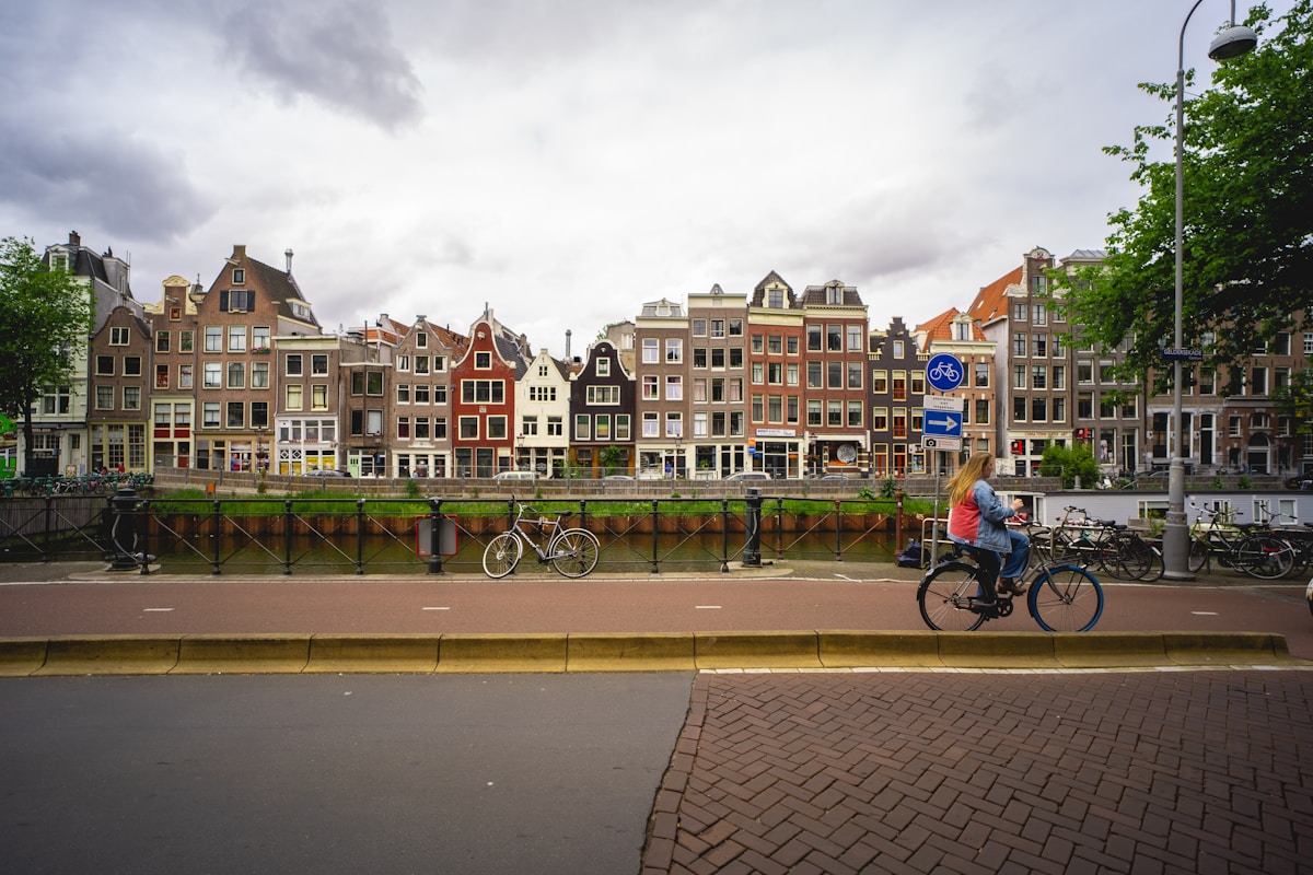 Cyclist passing traditional Dutch houses in Amsterdam